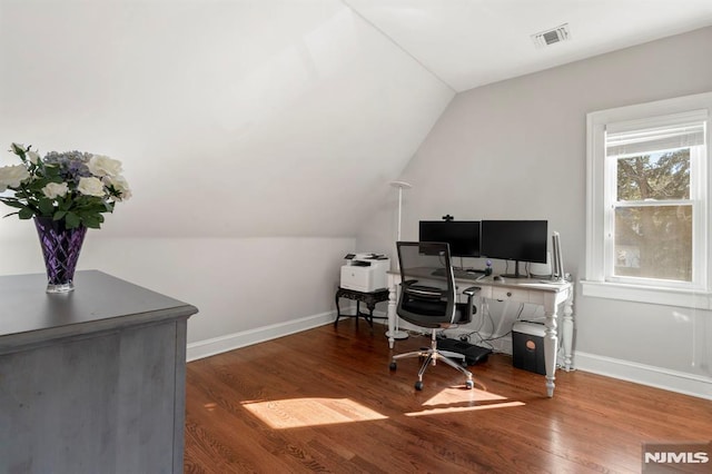 office space featuring vaulted ceiling, wood finished floors, visible vents, and baseboards