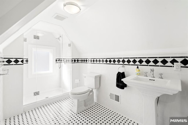 full bathroom with visible vents, toilet, a stall shower, tile walls, and vaulted ceiling