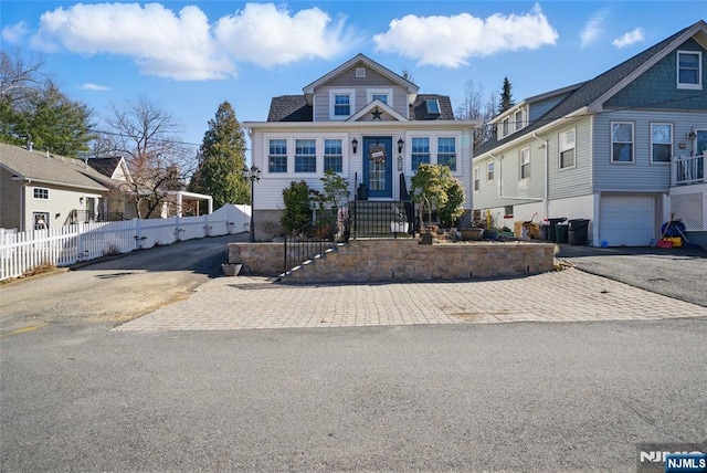 view of front of property with aphalt driveway, a garage, and fence