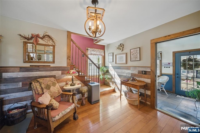 sitting room featuring hardwood / wood-style floors, a notable chandelier, stairs, and wainscoting