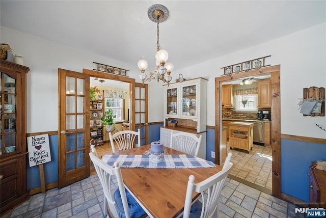 dining space with an inviting chandelier, stone tile floors, and french doors