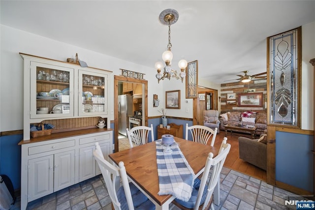 dining room with stone tile floors and ceiling fan with notable chandelier