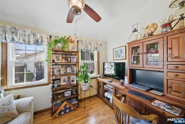 office space featuring baseboards, light wood-style flooring, a ceiling fan, and vaulted ceiling