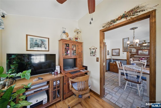 office featuring ceiling fan with notable chandelier, baseboards, and stone tile flooring