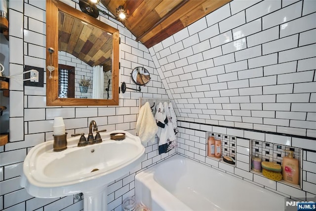 bathroom featuring lofted ceiling, a sink, wood ceiling, tile walls, and tasteful backsplash