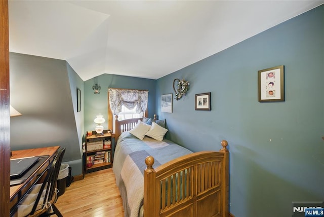 bedroom with light wood-style floors and lofted ceiling