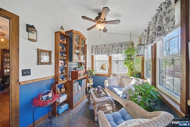 living area featuring stone finish flooring, ceiling fan, and vaulted ceiling