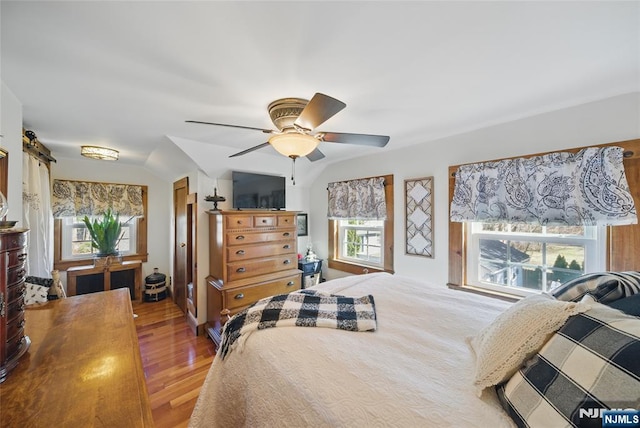 bedroom with ceiling fan, lofted ceiling, and wood finished floors