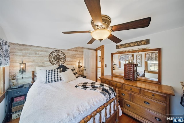 bedroom featuring wooden walls, an accent wall, and ceiling fan