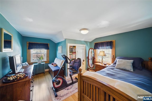 bedroom with a closet, light wood-style flooring, radiator heating unit, and vaulted ceiling