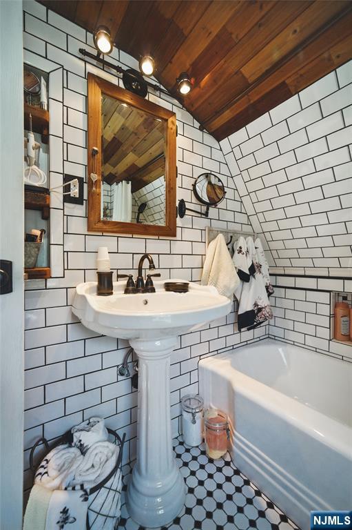 bathroom with wood ceiling, a bathing tub, tile walls, and walk in shower