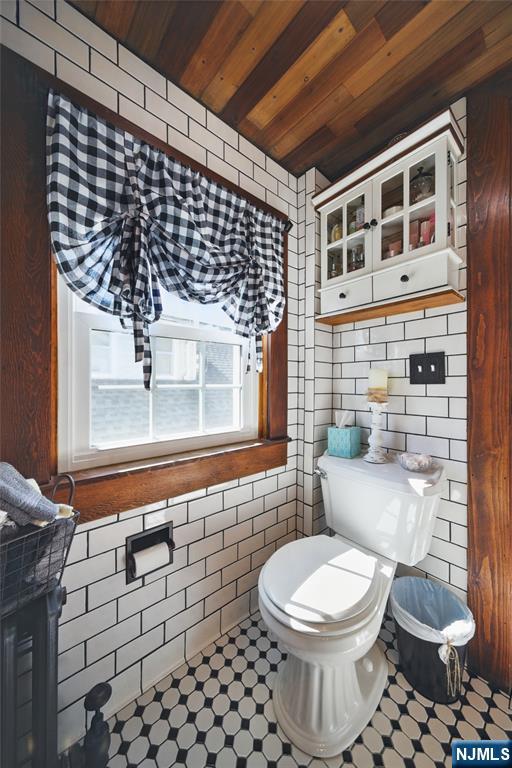 half bath with tile walls, toilet, and wood ceiling