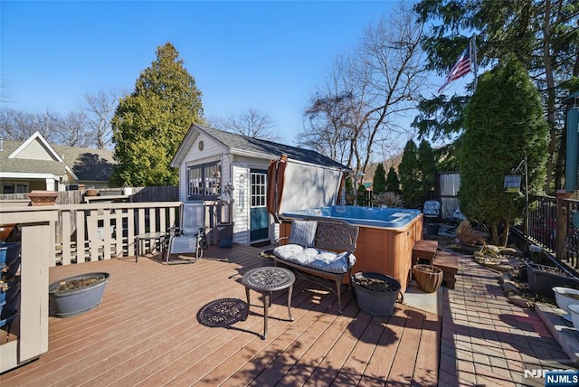 wooden deck featuring a fire pit, an outbuilding, fence, and a hot tub