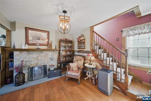 living area featuring stairway, a chandelier, a fireplace, and hardwood / wood-style flooring