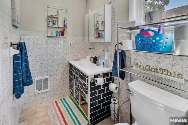 bathroom featuring visible vents, toilet, tile walls, and vanity