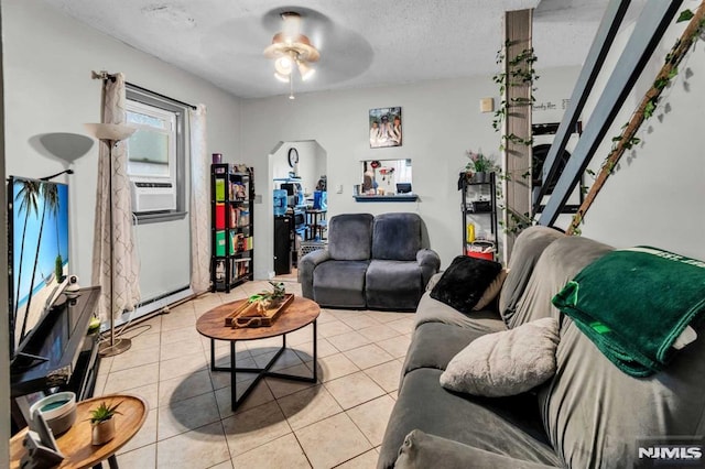 living area with light tile patterned floors, a baseboard radiator, a textured ceiling, and ceiling fan