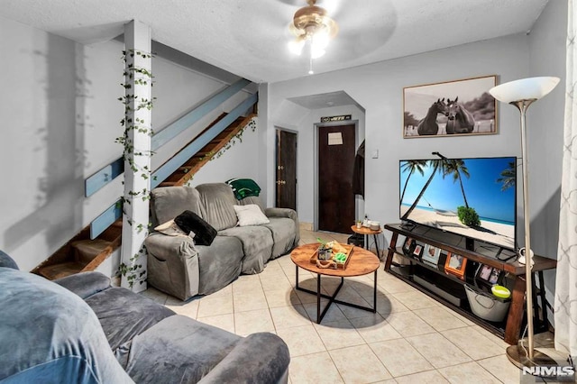 living room with tile patterned flooring, a textured ceiling, and stairs