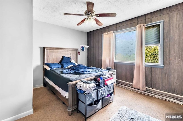 bedroom with baseboards, wooden walls, a textured ceiling, and ceiling fan