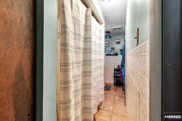 bathroom featuring tile patterned floors, visible vents, and a textured ceiling