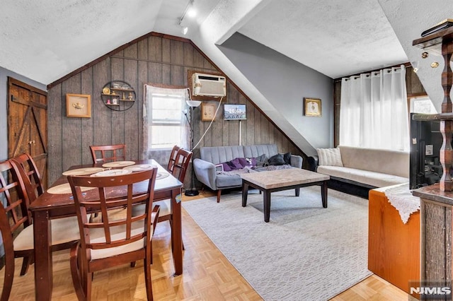 living area with wood walls, a textured ceiling, lofted ceiling, and a wall unit AC