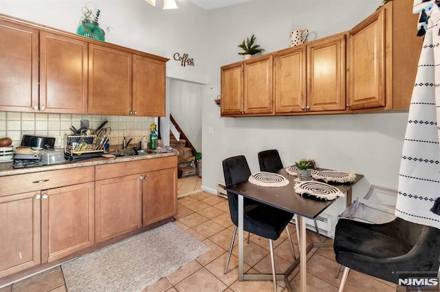 kitchen with a sink, brown cabinets, tasteful backsplash, and light tile patterned flooring