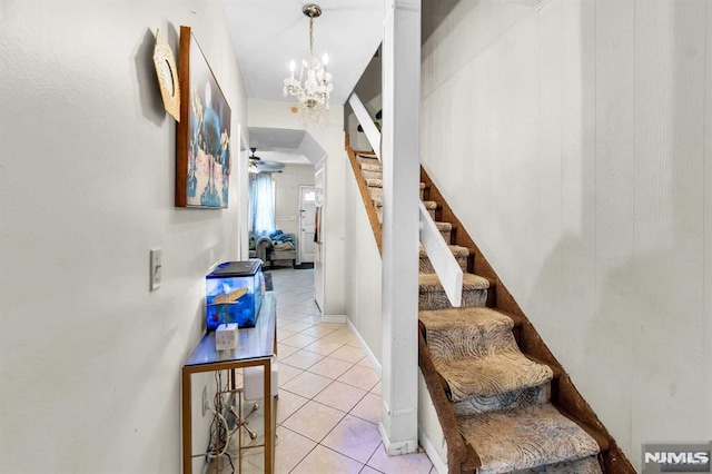 stairway featuring tile patterned floors and ceiling fan with notable chandelier