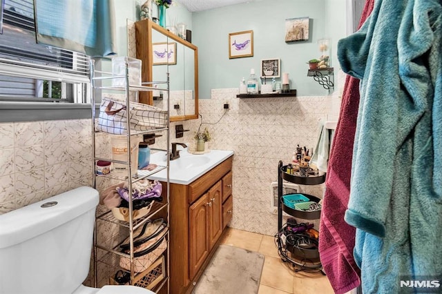 bathroom featuring vanity, tile walls, toilet, and wainscoting