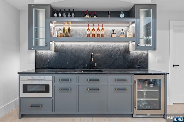 bar featuring baseboards, wet bar, a sink, wine cooler, and tasteful backsplash