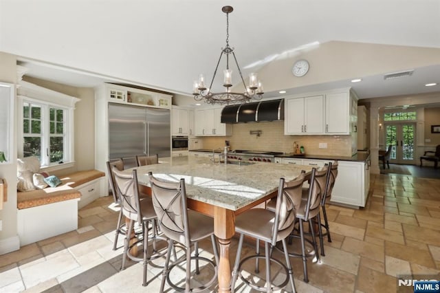 kitchen with exhaust hood, oven, visible vents, tasteful backsplash, and vaulted ceiling