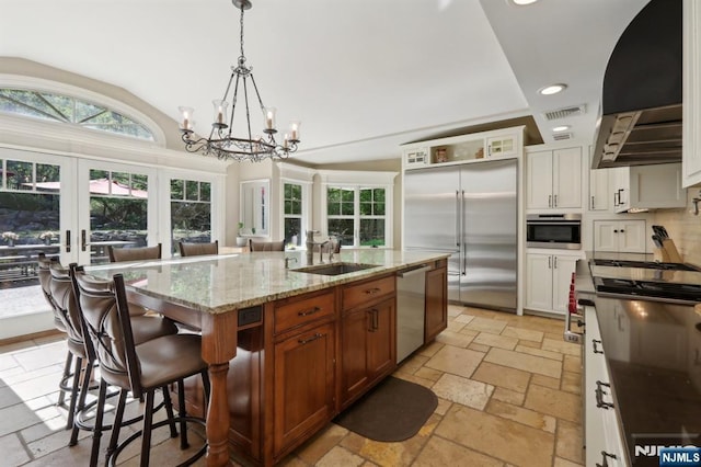 kitchen featuring stone tile floors, recessed lighting, a sink, appliances with stainless steel finishes, and a notable chandelier