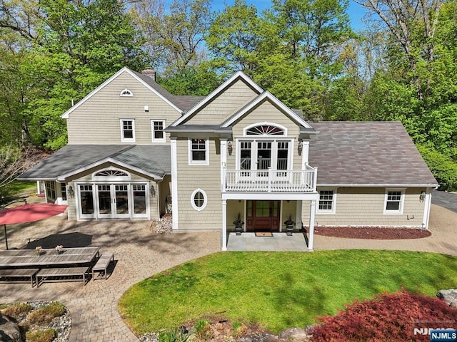 back of house with french doors, a patio area, a balcony, a yard, and a shingled roof