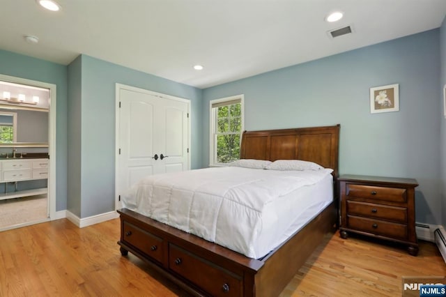 bedroom featuring a sink, light wood finished floors, baseboards, visible vents, and a closet