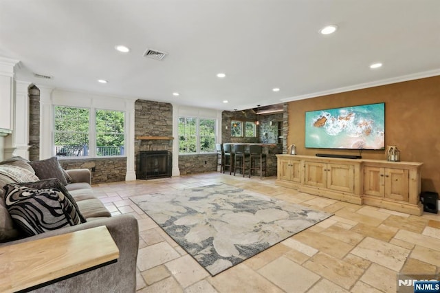 living room with crown molding, stone tile flooring, visible vents, a fireplace, and recessed lighting