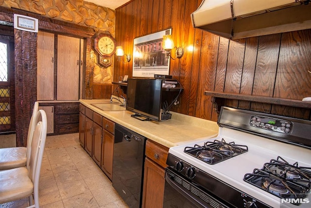 kitchen featuring range with gas stovetop, a sink, light countertops, under cabinet range hood, and dishwasher