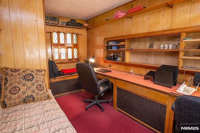 carpeted home office with wooden walls and built in desk