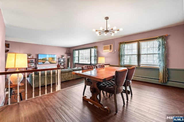 dining space with a baseboard heating unit, a wall unit AC, wood finished floors, and a chandelier