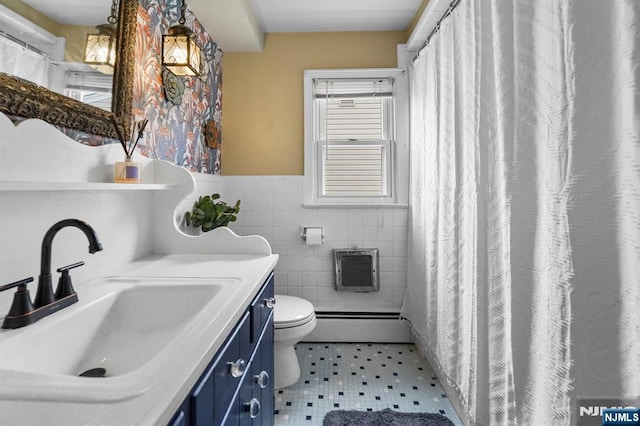 bathroom featuring toilet, vanity, wainscoting, tile walls, and a baseboard radiator