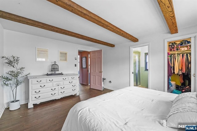 bedroom featuring beam ceiling, dark wood finished floors, a closet, baseboards, and a spacious closet