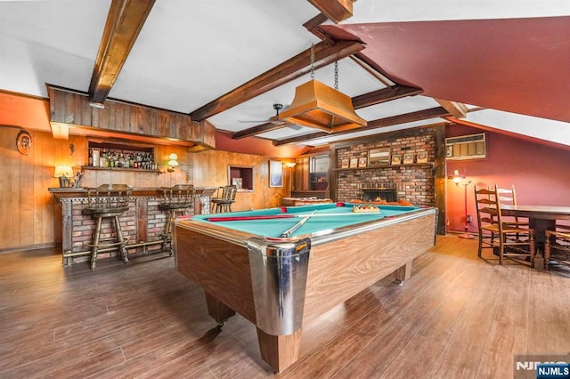 recreation room featuring a bar, beamed ceiling, wooden walls, and wood finished floors