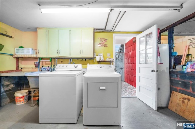 clothes washing area with a garage, cabinet space, independent washer and dryer, and a sink