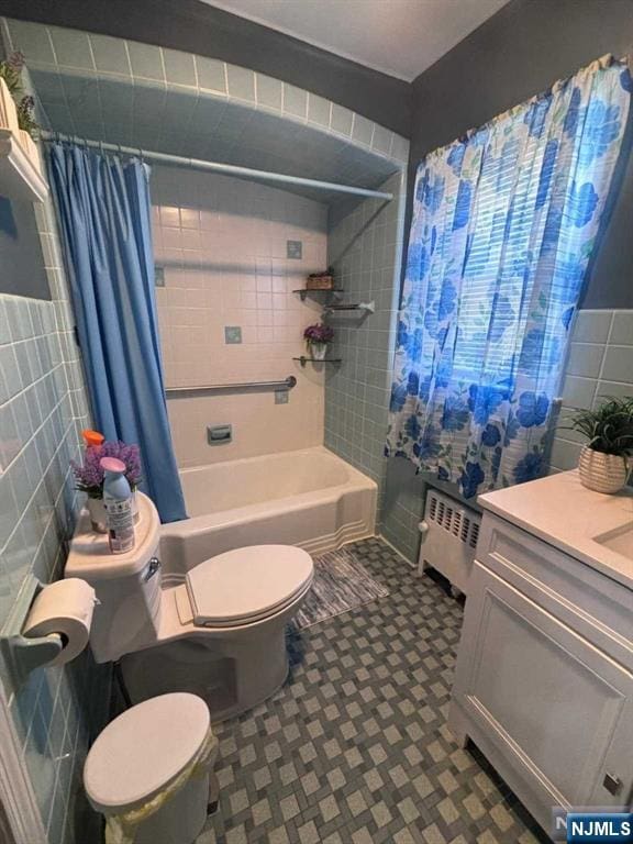 bathroom with toilet, shower / bath combo, radiator, tile walls, and vanity