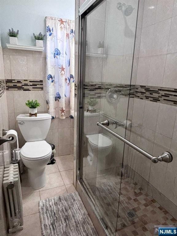 full bathroom with toilet, a stall shower, radiator heating unit, tile walls, and tile patterned flooring