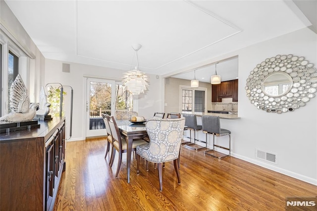 dining space with visible vents, an inviting chandelier, baseboards, and wood finished floors