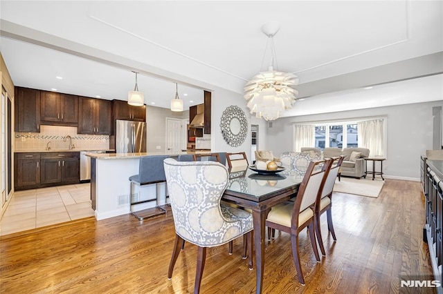 dining room featuring an inviting chandelier, light wood-style floors, and baseboards