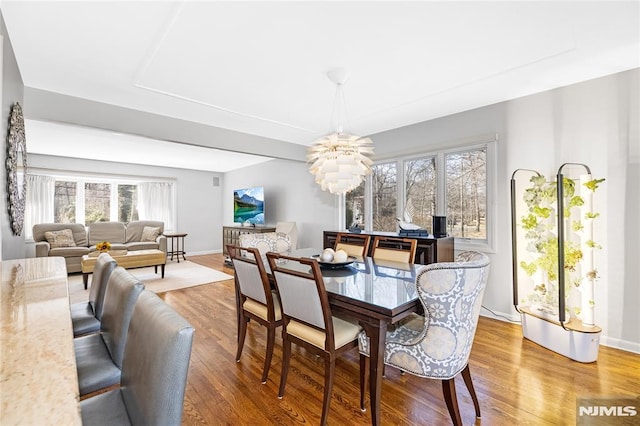 dining room featuring a chandelier, baseboards, and wood finished floors