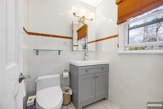 bathroom with vanity, tile walls, toilet, and tile patterned flooring