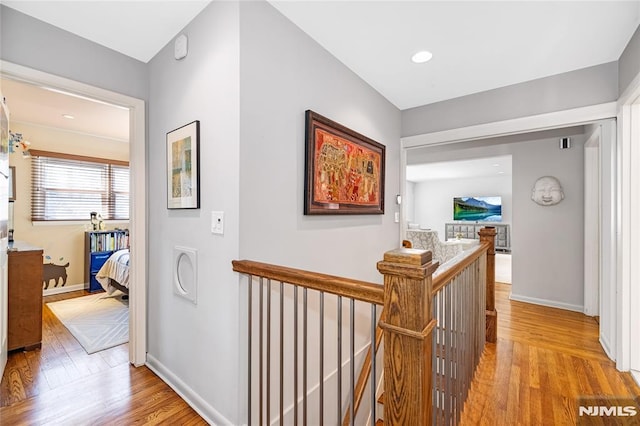 hallway with baseboards, an upstairs landing, and wood finished floors