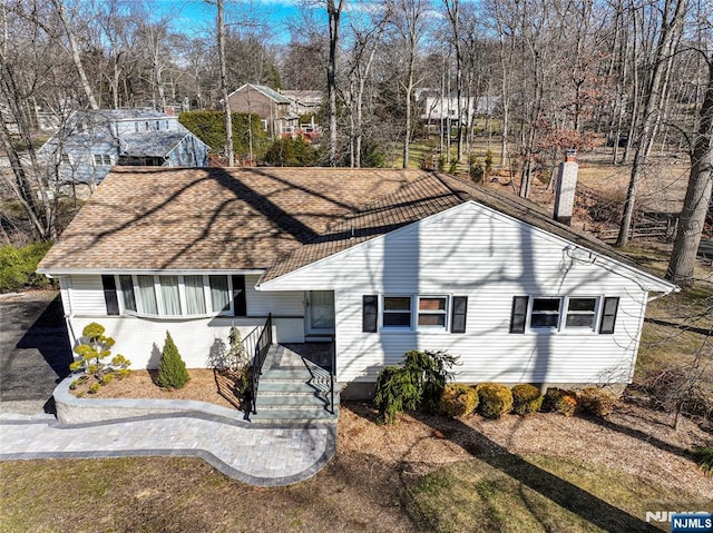 view of front of home with a chimney and roof with shingles