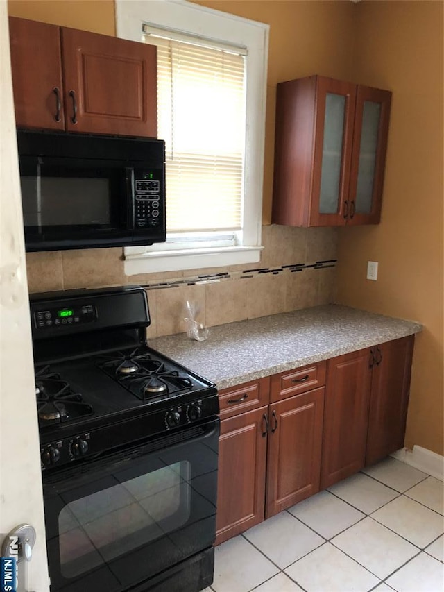 kitchen with backsplash, glass insert cabinets, light countertops, brown cabinets, and black appliances