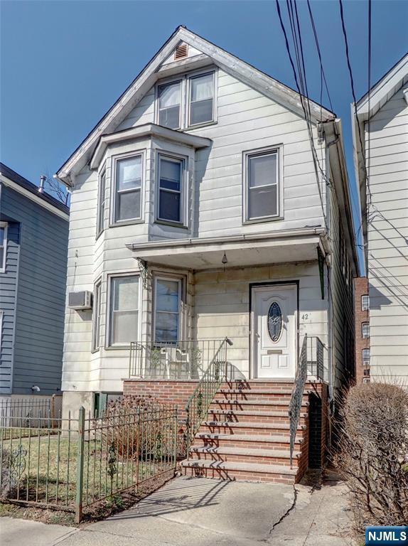 view of front of home featuring a fenced front yard, a porch, and an AC wall unit